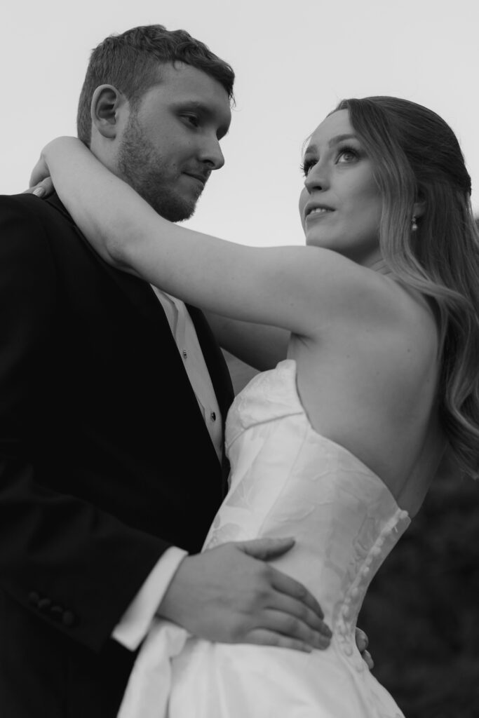Groom looking at bride as she looks off at the sunset during couple sunset photos.