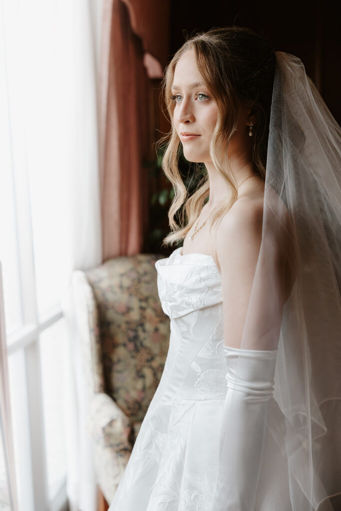 Bride getting ready and looking out window.